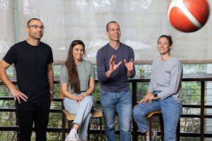 שמוליק ברנר זורק כדורסל לצד אנשי ספורט בקמפוס